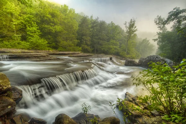 一缕美丽的溪流瀑布 长期暴露 还有公园里长满树木的大石头 — 图库照片