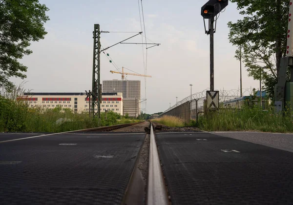 Metalik Demiryollarına Binalara Karşı Boş Bir Asfalt Yol Manzarası — Stok fotoğraf