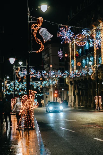 Pionowe Ujęcie Samochodu Jadącego Pustej Ulicy Ozdobionej Lampkami Świątecznymi Nocy — Zdjęcie stockowe