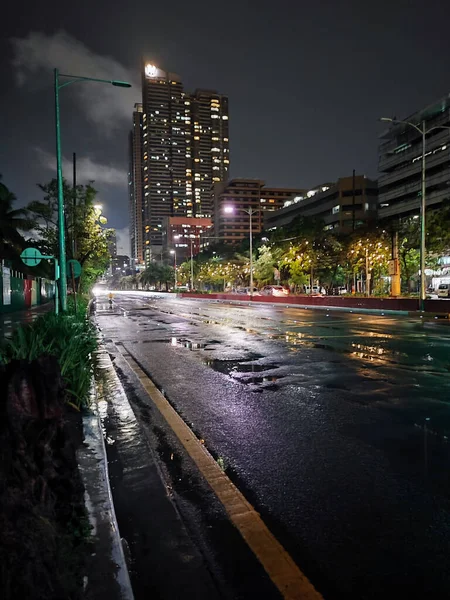 马尼拉一条潮湿的夜晚街道上高楼和路灯的垂直拍摄 — 图库照片