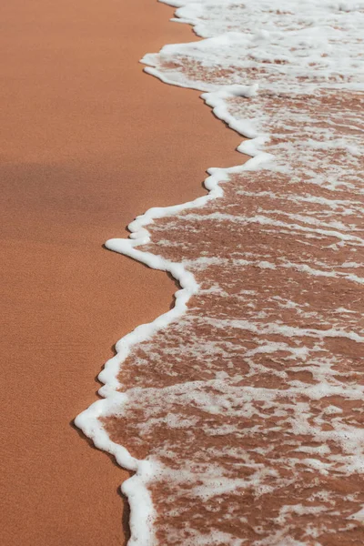在棕色的海岸上的一个垂直的泡沫波的镜头 — 图库照片