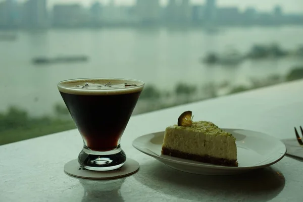 武漢市のスカイラインと長江のぼやけた景色を望むコーヒーとデザートのカップの選択的な焦点ショット — ストック写真