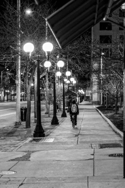一个男人背着背包在晚上骑自行车的后视镜 — 图库照片