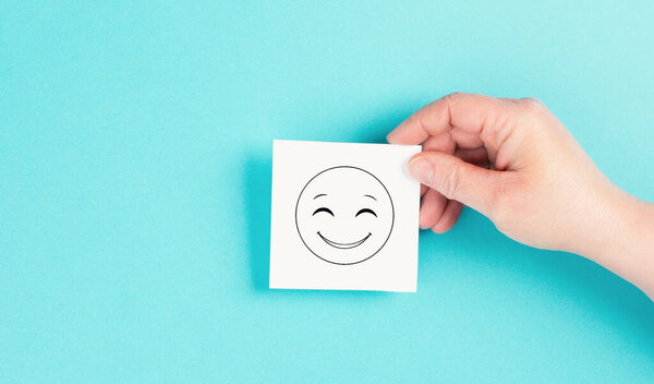 Smiling happy face on a paper, positive emotions, good customer feedback, laughing, blue backgrounds