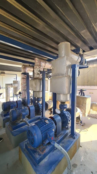 A vertical shot of a water pumping station with blue pumps