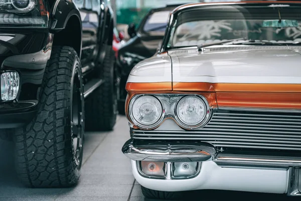 一辆老式的白色和橙色复古汽车在大街上与现代汽车并排行驶的前景 — 图库照片
