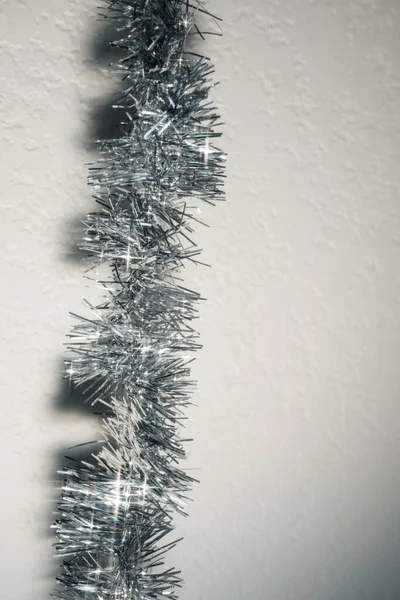 Sparkly Zilveren Tinsel Slinger Decoratie Tegen Witte Muur Achtergrond Kopieerruimte — Stockfoto