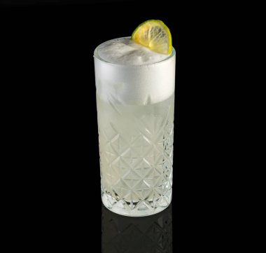 Siyah arka plan üzerinde limon dilimi olan bir bardak kokteylin yakın çekimi.