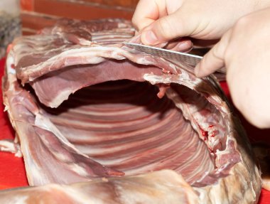 Yetenekli bir şef akşam yemeği hazırlığı için bir kuzu pirzolası dilimledi.