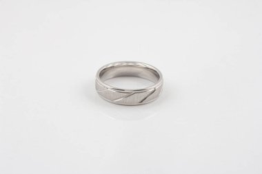 Beyaz arka planda izole edilmiş basit desenleri olan gümüş bir halkanın yakın çekimi