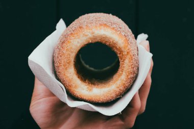 Kağıt peçeteye şekerli bir çörek koyulaştıran biri.