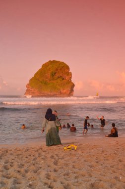 Kumsalda dinlenen insanların olduğu bir sahil manzarası. Goa Çin, Malang, Doğu Java sahillerinde salgın bittikten sonra bayram tatili