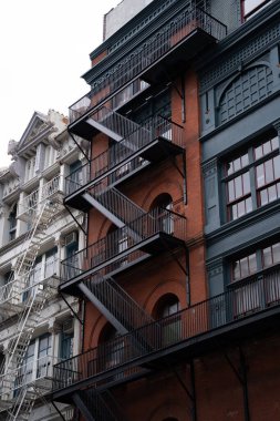 Yangın merdiveni olan tuğla binanın ön cephesinin dikey çekimi.