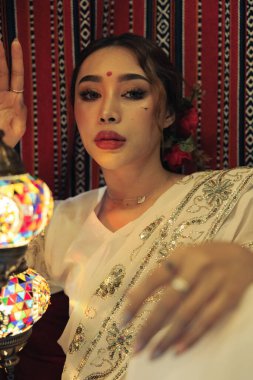 Güzel bir lamba tutan Güney Asyalı bir kadının dikey çekimi.