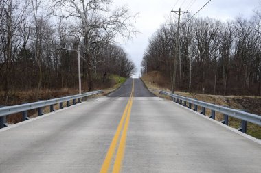 Yapraksız ağaçların ortasında boş bir otoyol