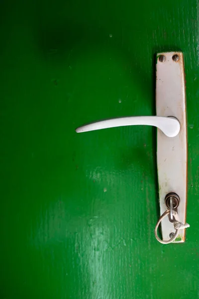 緑のドアにキーを持つ白いハンドルの垂直閉鎖 — ストック写真