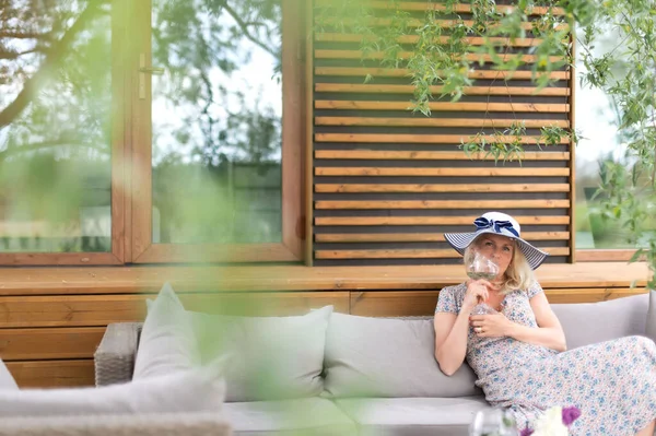 Vacker Kvinna Sommarklänning Med Ett Vinglas Sittande Grå Soffa Trädgård — Stockfoto