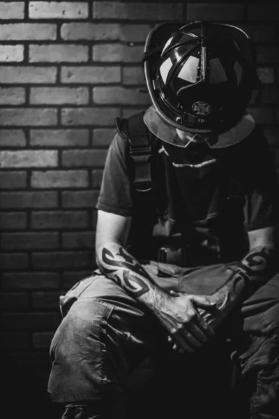Een Verticale Grijsschaal Close Van Getatoeëerde Brandweerman Met Helm Zittend — Stockfoto
