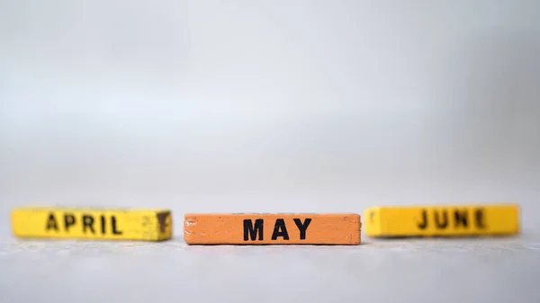 A close-up shot of three wooden blocks of May, April, and June months.
