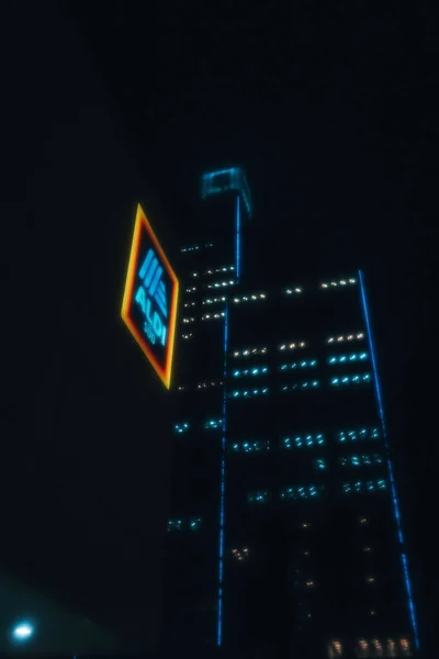 夜の背景にライトアップされた高層ビルとアルディのスーパーマーケットの看板の低角度ショット — ストック写真