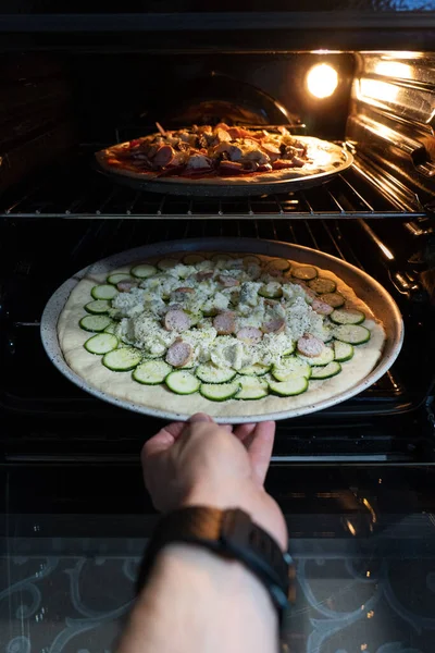 Ręka Wkładająca Niegotowaną Pizzę Piekarnika — Zdjęcie stockowe