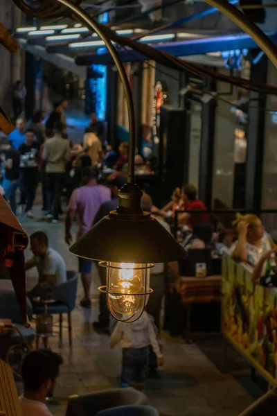 イスタンブールの屋外レストランに座っている人々の垂直ショット前景にランプが付いている — ストック写真
