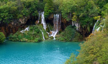 Ağaçlarla çevrili turkuaz nehirli büyüleyici şelale manzarası