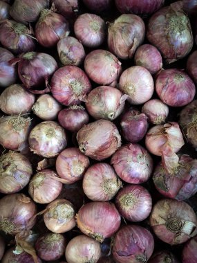 Bir marketteki kırmızı soğan yığınının dikey görüntüsü.