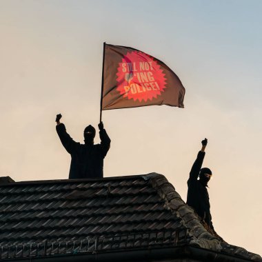 Çatıda iki siyah giysili protestocu ellerinde 