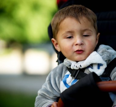 Siyah bir arka planda bebek koltuğunda oturan güzel beyaz bir çocuğun portresi.