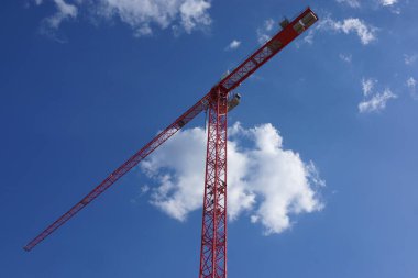 Mavi gökyüzünde beyaz bulutlu kırmızı vinç silueti. Renklerin güzel karşıtlığı.