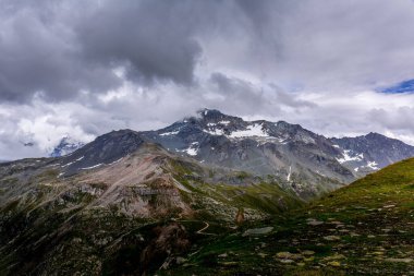 Bulutlu gökyüzüne karşı kayalık dağ sırasının manzarası. La Plagne, Bellecote, Fransa.