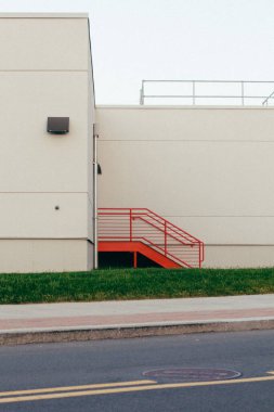 Endüstriyel bir deponun yanındaki kırmızı merdivenlerin dikey görüntüsü.