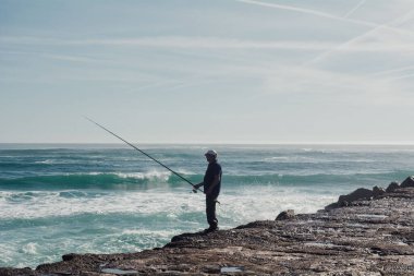 Portekiz, Lizbon 'da bir deniz kıyısında balık yakalamaya çalışan bir balıkçı.