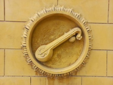 Sarı tuğla duvarda daire şeklinde bir heykel..