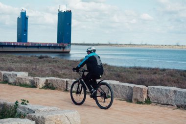 Gündüz vakti kasklı bisiklet süren genç bir adam.