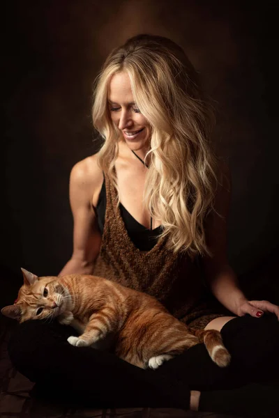 膝の上に猫が横になっている若い白人女性の垂直ショット — ストック写真