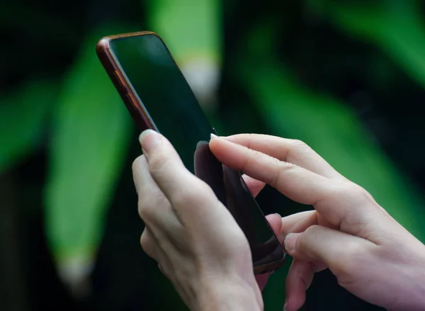 ぼやけた黒と緑の背景に隔離された携帯電話に入力する女性の閉鎖 — ストック写真