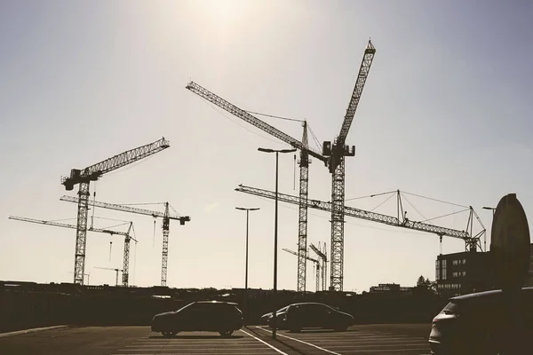 Tiro Ângulo Baixo Guindastes Construção Contra Estacionamento Carros Dia Ensolarado — Fotografia de Stock