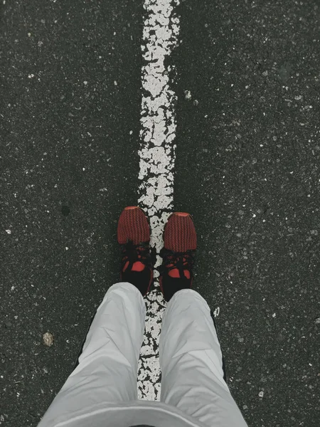 Kırmızı Koşu Ayakkabılarıyla Beyaz Çizgili Bir Yolda Duran Birinin Dikey — Stok fotoğraf