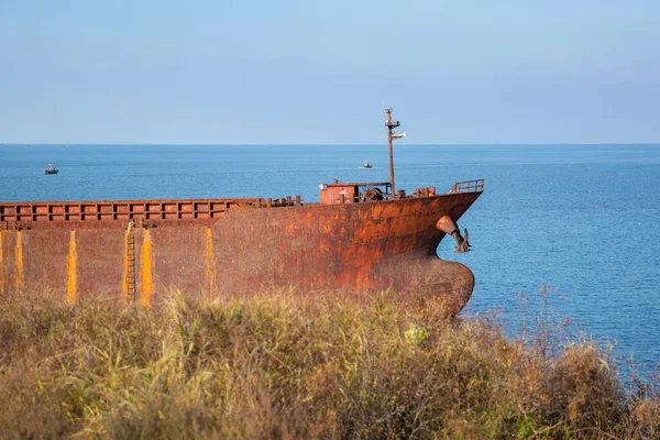 岩の多い海岸から捕獲された穏やかな海の上に捨てられた錆びた船 — ストック写真