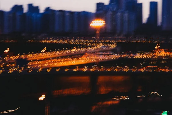 Hosszú Expozíciós Felvétel Egy Kivilágított Hídról Épületekkel Háttérben Alkonyatkor — Stock Fotó
