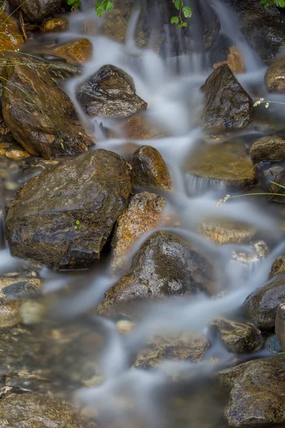Ormanda güneş ışığıyla taşan taşların arasından taşan azgın bir nehrin güzel bir görüntüsü.