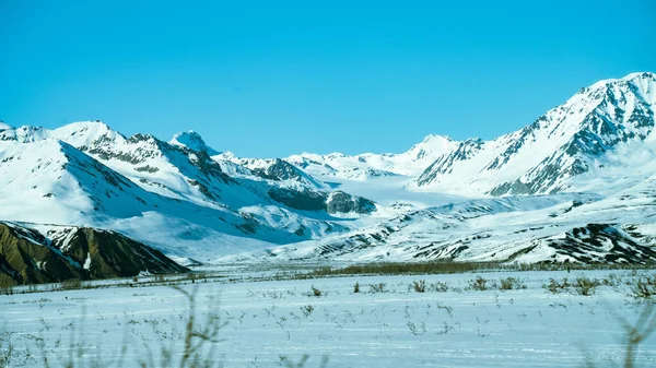 A beautiful view of a snowy mountain range with landscape in the foreground