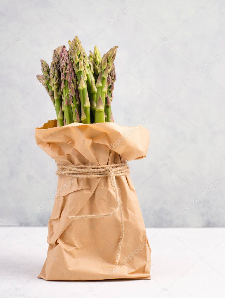 Fresh green bundle of asparagus on a white textured table, vegetables in spring, gourmet cuisine food, cooking a vegan meal