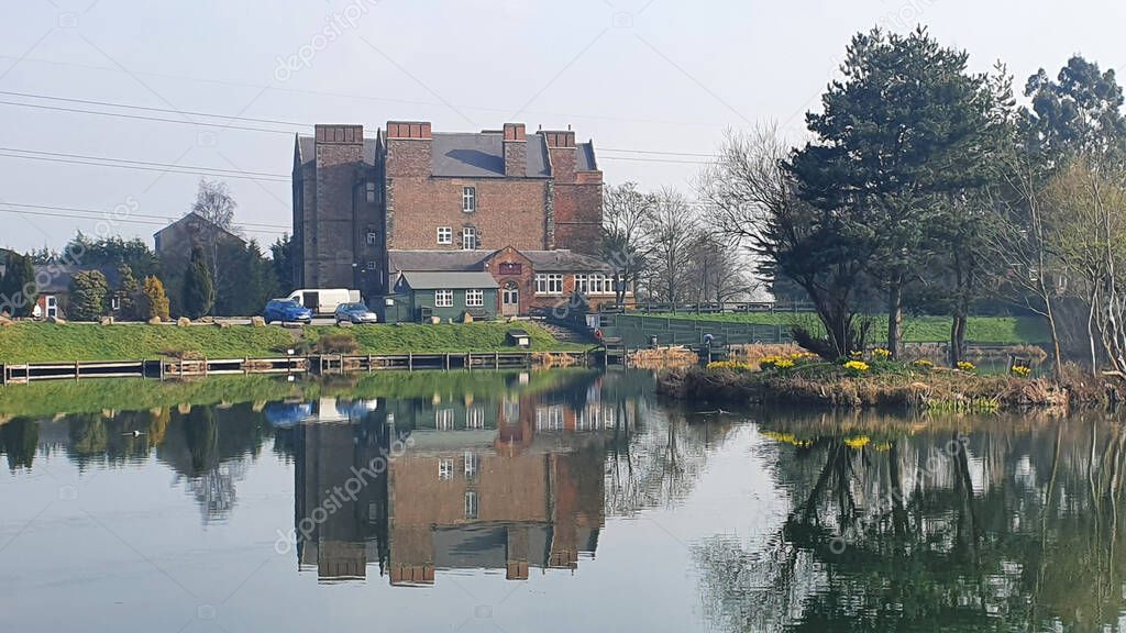 A distant view of the Weston on Trent village reflecting on the lake in Derbyshire, England