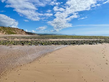 Bulutlu bir gökyüzünün altında kumlu bir sahilde güzel bir kaya görüntüsü..