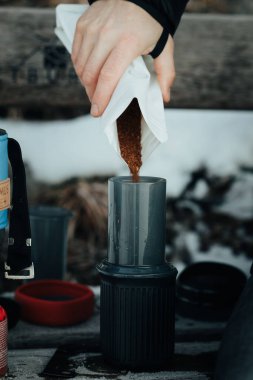 Bir insanın baharat döken elinin dikey görüntüsü bir torbadan kavanoza karışıyor.