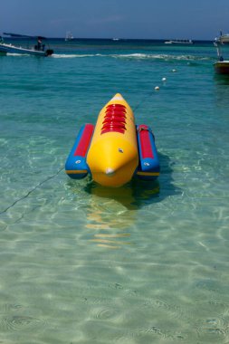 Sakin bir sahilde yüzen muz teknesinin dikey görüntüsü.