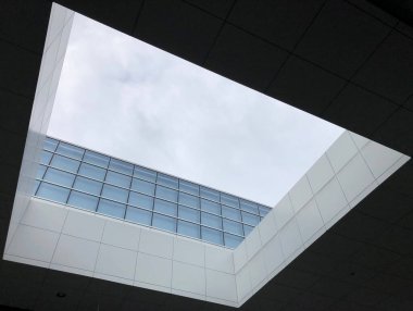 Gökyüzü manzaralı bir binanın çatısındaki kare bir deliğin alçak açılı görüntüsü.